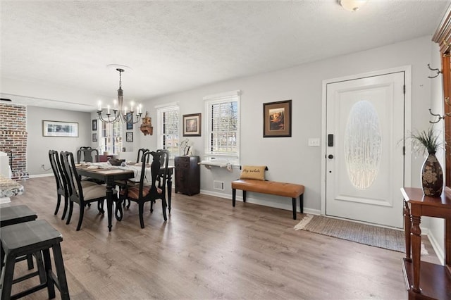 dining space with light wood finished floors, a textured ceiling, and an inviting chandelier