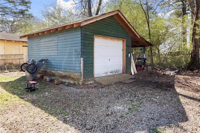 detached garage featuring fence and driveway