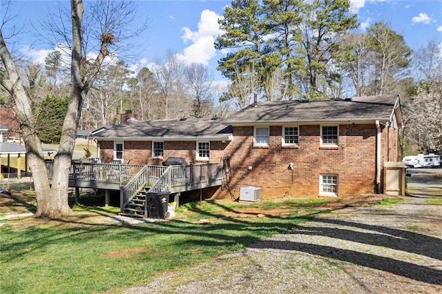 back of house featuring a lawn, a chimney, a deck, brick siding, and stairs