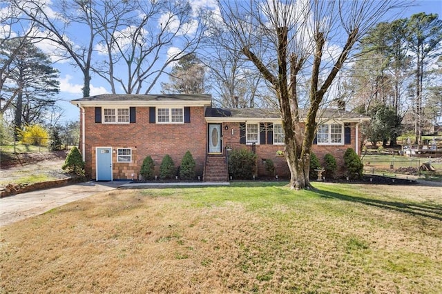 tri-level home with brick siding, a chimney, a front yard, and fence