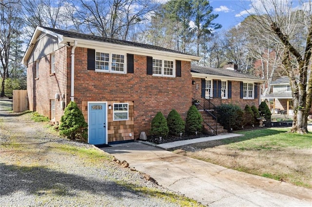 tri-level home featuring driveway, brick siding, board and batten siding, and a chimney