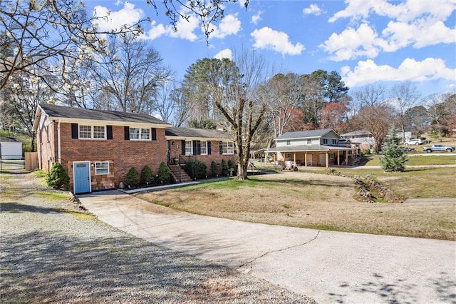 split level home with a front yard, brick siding, and driveway