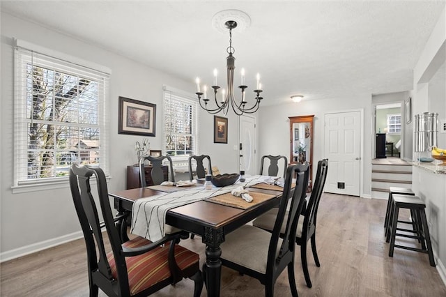 dining space with baseboards, light wood-style floors, and a chandelier