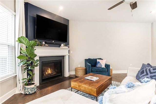 living area with a wealth of natural light, a glass covered fireplace, and baseboards