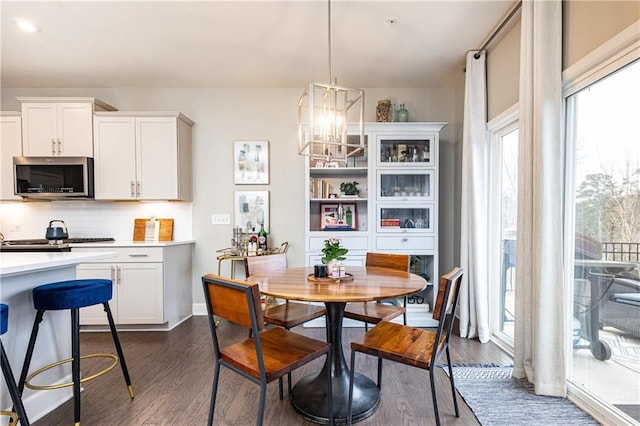 dining space with dark wood-style floors, baseboards, and a notable chandelier