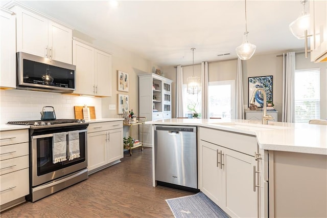 kitchen featuring stainless steel appliances, light countertops, white cabinetry, and pendant lighting