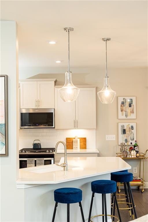 kitchen with appliances with stainless steel finishes, white cabinets, light countertops, and decorative light fixtures