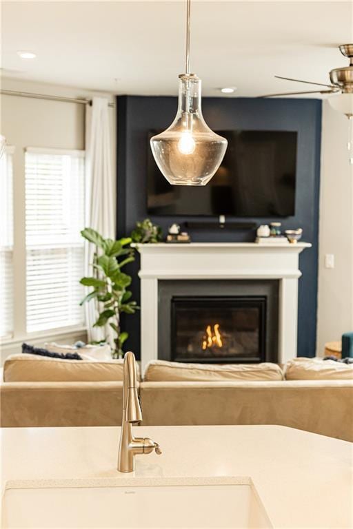 living area with a ceiling fan and a glass covered fireplace