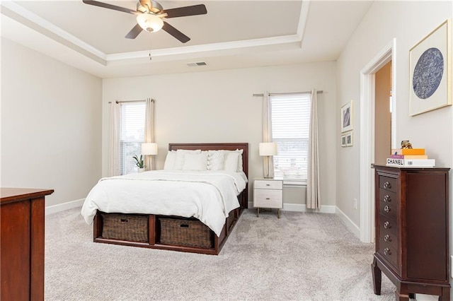 bedroom with a tray ceiling, multiple windows, and baseboards