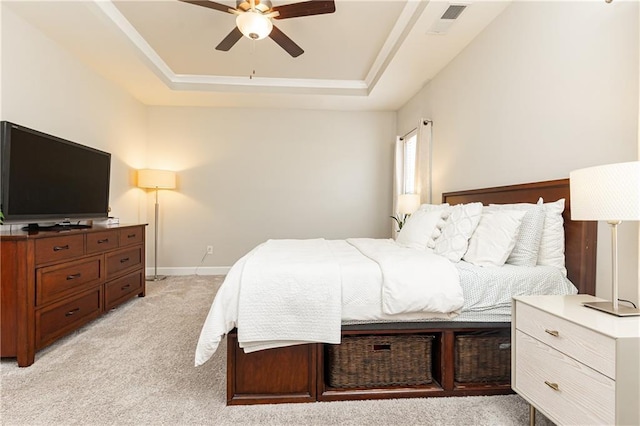 bedroom featuring light colored carpet, a ceiling fan, visible vents, baseboards, and a tray ceiling