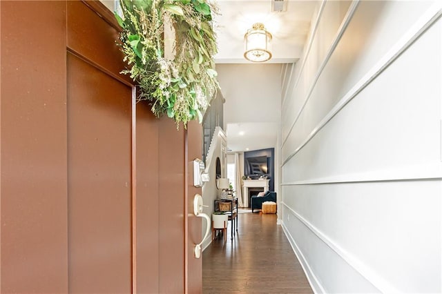 hallway featuring a towering ceiling and dark wood-style floors