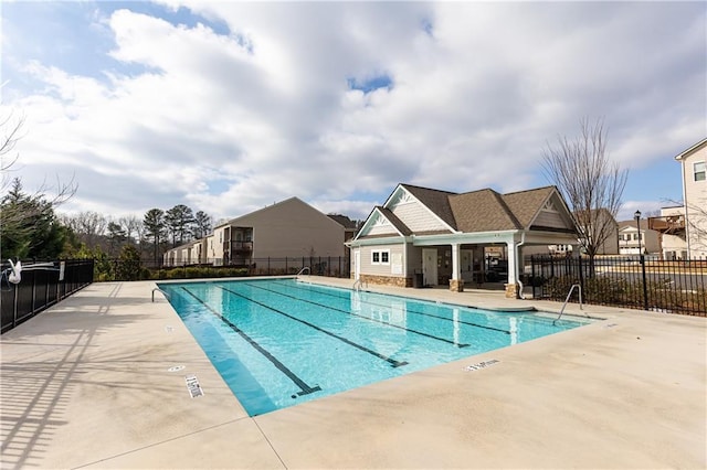 community pool with a patio area and fence