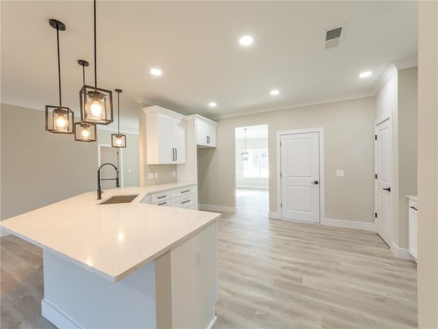 kitchen featuring decorative light fixtures, white cabinetry, sink, kitchen peninsula, and light wood-type flooring