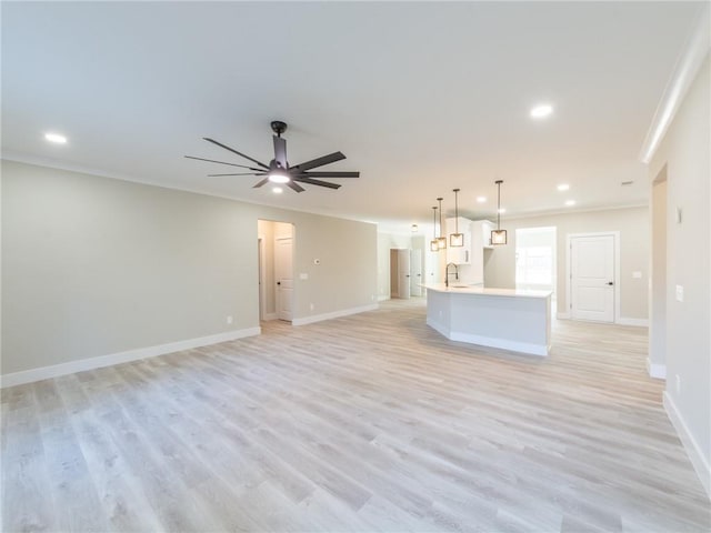 unfurnished living room with light wood-type flooring, ceiling fan, crown molding, and sink