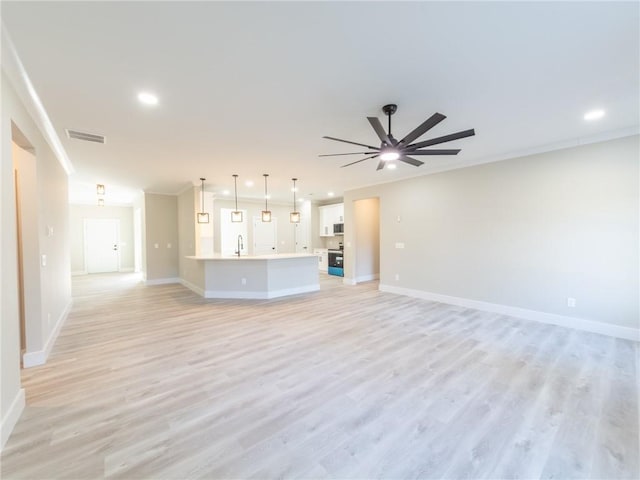 unfurnished living room with ceiling fan, sink, ornamental molding, and light hardwood / wood-style floors