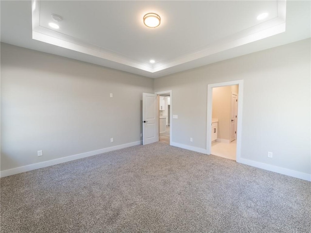 unfurnished bedroom with a raised ceiling, carpet floors, and connected bathroom