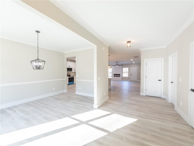 unfurnished living room featuring ceiling fan with notable chandelier, light hardwood / wood-style flooring, and ornamental molding