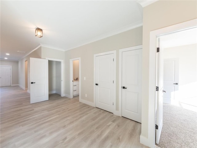 unfurnished bedroom featuring light wood-type flooring, ensuite bathroom, and ornamental molding