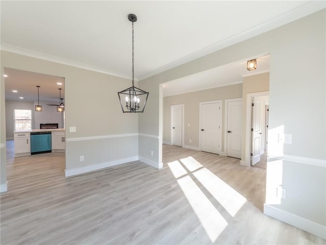 unfurnished dining area featuring light hardwood / wood-style flooring, crown molding, and a chandelier