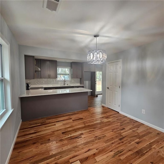 487 Eastside Dr, Dacula, GA 30019 - kitchen featuring a peninsula, gray cabinetry, light countertops, a chandelier, and tasteful backsplash
