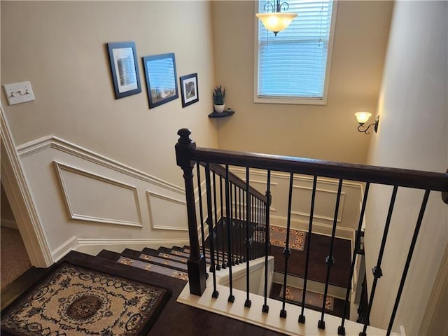 staircase with wainscoting and a decorative wall