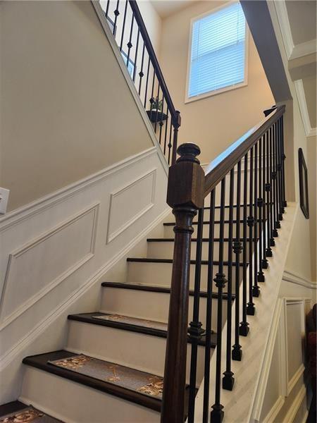 stairway featuring a wainscoted wall, ornamental molding, and a decorative wall