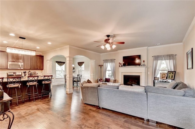 1211 Chapel Estates Way, Dacula, GA 30019 - living room with decorative columns, arched walkways, a ceiling fan, light wood-type flooring, and ornamental molding