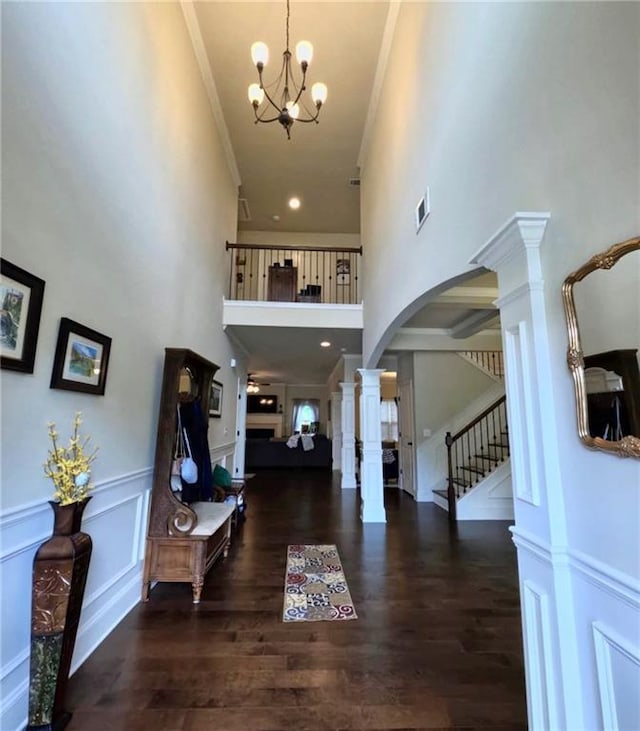 entryway featuring crown molding, a chandelier, decorative columns, and a towering ceiling