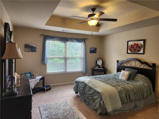bedroom with visible vents, baseboards, ceiling fan, a raised ceiling, and carpet flooring