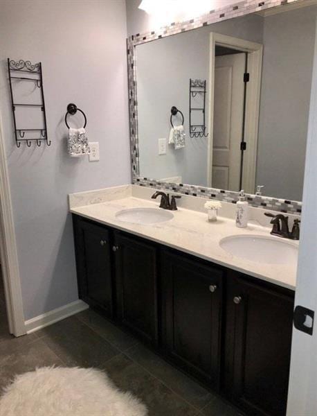 bathroom featuring double vanity, a sink, and baseboards