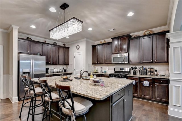 1211 Chapel Estates Way, Dacula, GA 30019 - kitchen featuring appliances with stainless steel finishes, ornamental molding, dark brown cabinetry, a kitchen bar, and hanging light fixtures
