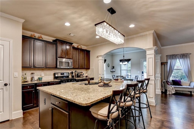 1211 Chapel Estates Way, Dacula, GA 30019 - kitchen with stainless steel appliances, decorative columns, arched walkways, a chandelier, and light stone counters