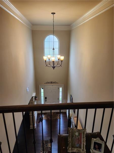 entrance foyer featuring stairs, ornamental molding, wood finished floors, and an inviting chandelier