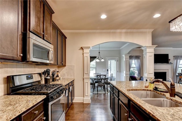1211 Chapel Estates Way, Dacula, GA 30019 - kitchen featuring appliances with stainless steel finishes, ornate columns, arched walkways, dark wood-type flooring, and light stone counters