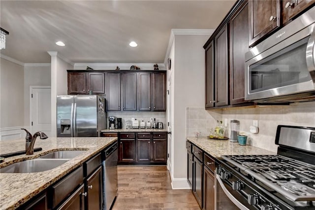 1211 Chapel Estates Way, Dacula, GA 30019 - kitchen featuring stainless steel appliances, ornamental molding, dark brown cabinets, light stone countertops, and light wood-type flooring