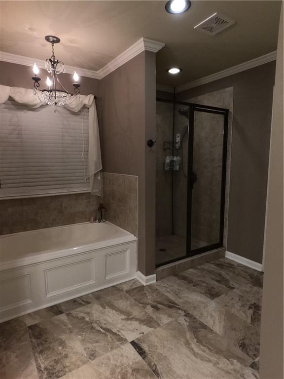 bathroom featuring ornamental molding, a shower stall, a garden tub, and visible vents