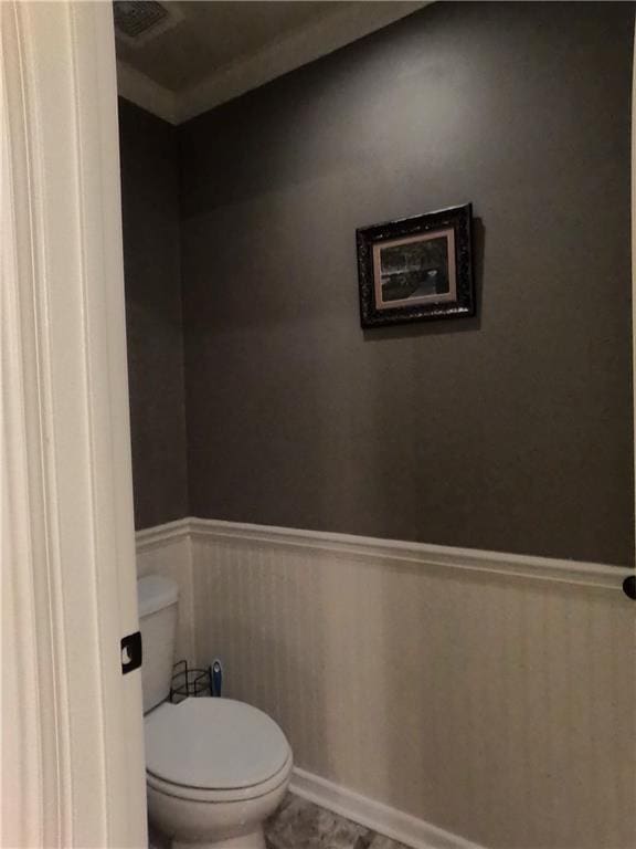 bathroom with baseboards, wainscoting, and toilet