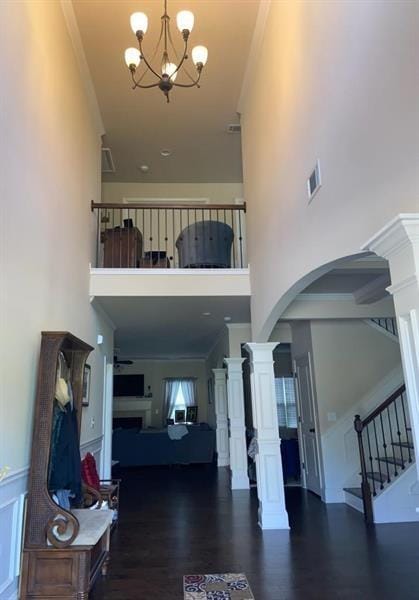 foyer entrance featuring crown molding, a fireplace, visible vents, stairway, and ornate columns