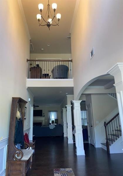 entryway with visible vents, a towering ceiling, arched walkways, an inviting chandelier, and stairs