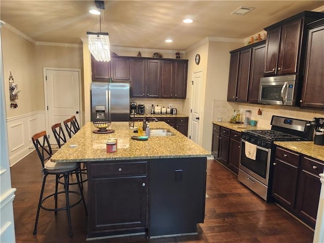 kitchen with dark wood finished floors, a breakfast bar area, stainless steel appliances, visible vents, and a sink