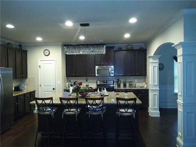 kitchen featuring ornamental molding, decorative backsplash, ornate columns, dark wood finished floors, and appliances with stainless steel finishes