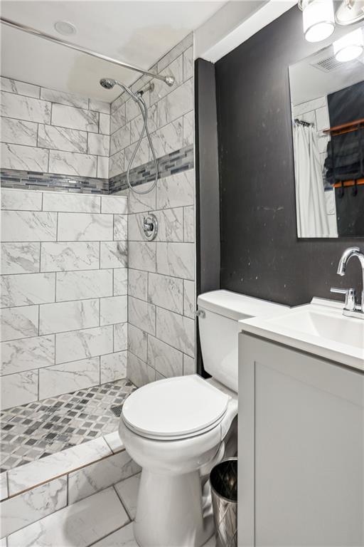 877 Lee Andrews Ave SE, Atlanta, GA 30315 - bathroom with toilet, a tile shower, visible vents, marble finish floor, and vanity