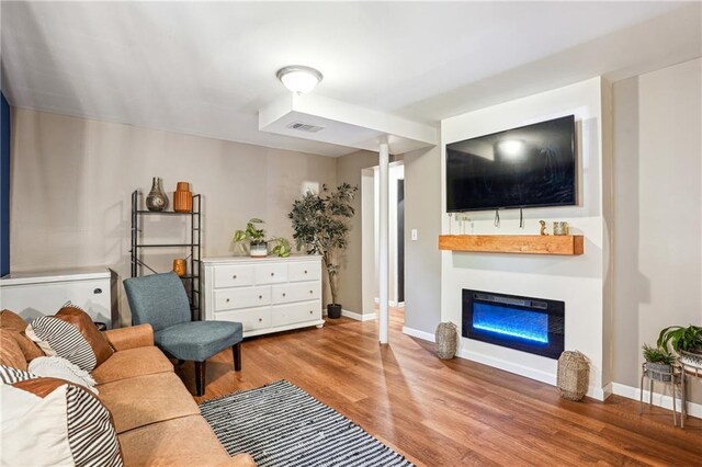 877 Lee Andrews Ave SE, Atlanta, GA 30315 - living area with a glass covered fireplace, wood finished floors, visible vents, and baseboards