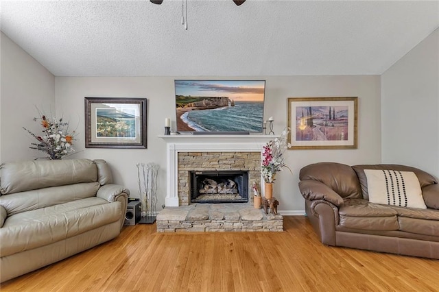 503 Silver Maple Ln, Woodstock, GA 30189 - living room with ceiling fan, wood finished floors, a fireplace, a textured ceiling, and baseboards