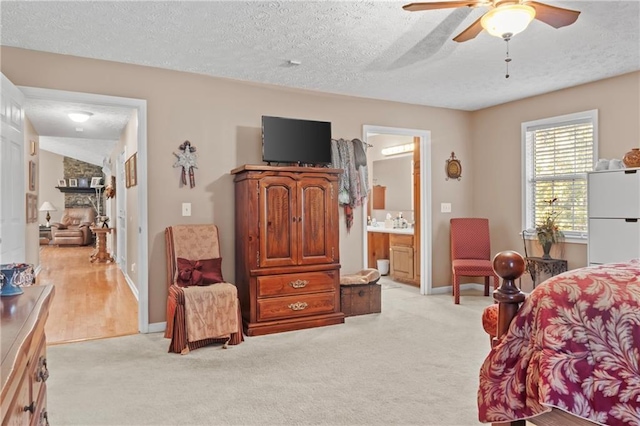 bedroom with light carpet, baseboards, connected bathroom, a textured ceiling, and a fireplace