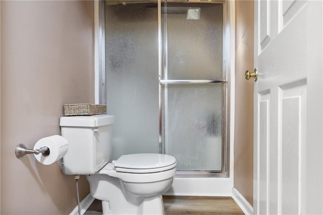 full bathroom featuring baseboards, a shower stall, toilet, and wood finished floors