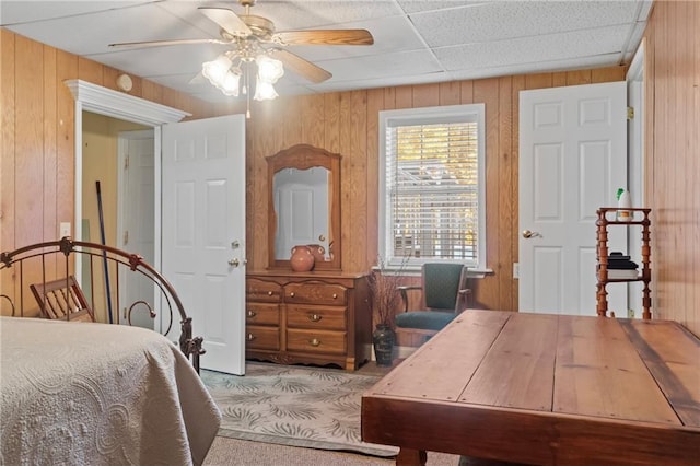 bedroom with ceiling fan and wooden walls