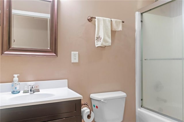 bathroom featuring toilet, enclosed tub / shower combo, and vanity