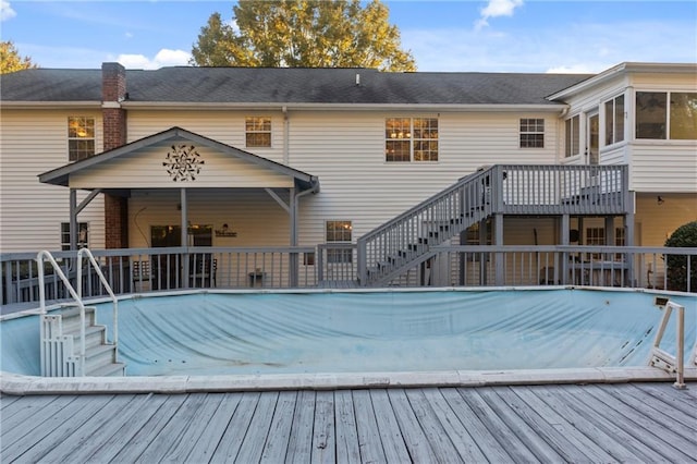 view of swimming pool featuring a deck, stairway, a sunroom, and a covered pool