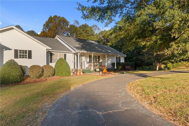 ranch-style house with covered porch, driveway, and a front lawn